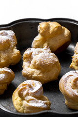 Decorating profiteroles with powdered sugar. Eclairs with icing sugar