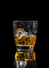 Whisky glass with ice on black background