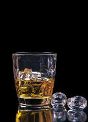 Whisky glass with ice on black background