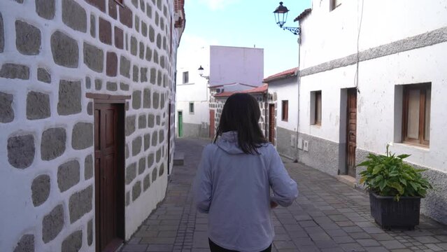 Woman walking through Tejeda town in Gran Canaria. Rear view of young girl visiting Tejeda narrow streets
