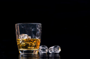 Whisky glass with ice on black background