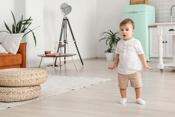 Lovely little boy in white shirt standing in living room. Lovely child posing and looking away