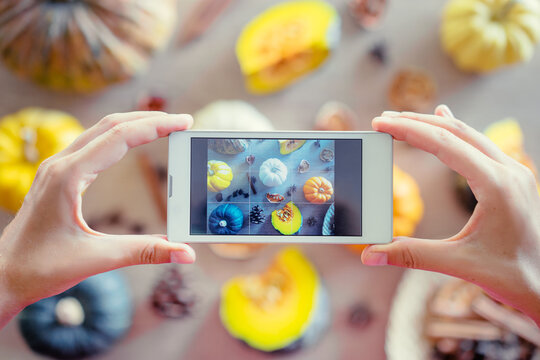 Close up of hands holding smartphone, taking photo of colorful vegetables on wooden table.