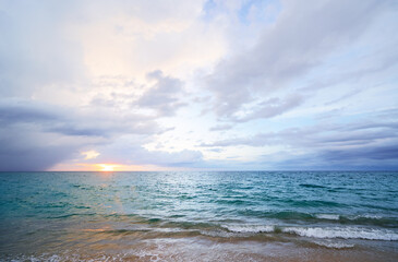 Seascape with sunset on the ocean shore. Beautiful cloudy sky.
