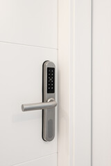 Naklejka premium Entrance white wooden door with an electronic lock for the security of the apartment. On the lock there are buttons with numbers for entering the code. Chrome metal lock.