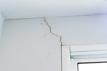 Wall crack near window frame in house or office interior building. Wall concrete broken from...