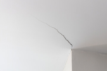Ceiling room crack in house or office building. Home ceiling broken from structure interior foundation problem concept.