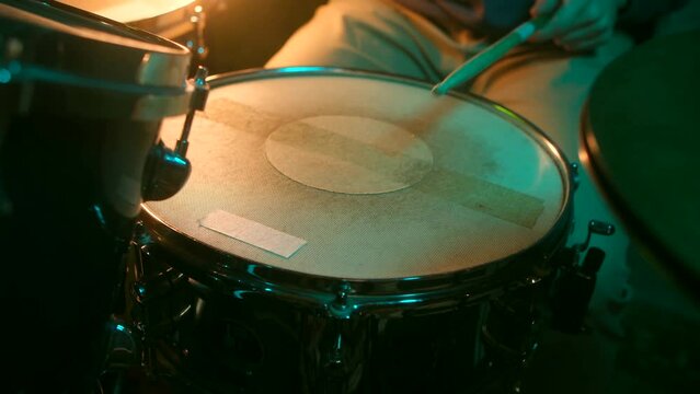 close up - the drummer plays with sticks on drums in neon lights, home lesson paradiddle training. slowmotion.
