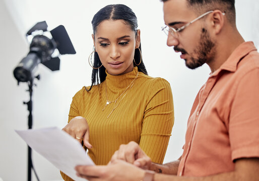 Documents, collaboration or planning with a photographer and model talking in a studio for creative production. Teamwork, designer or fashion with a designer man and woman at work on a magazine shoot