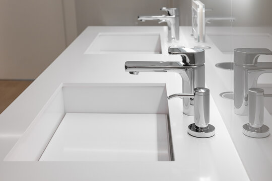 Side view of double white sink with large and small taps for filtering running water for drinking. Concept of modern filtration system and design
