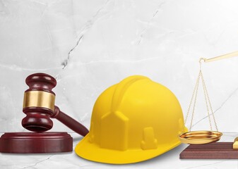 Judge's wooden hammer and worker helmet on the desk