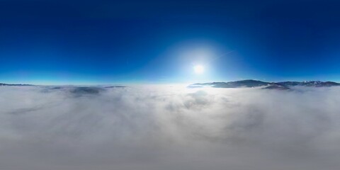360 panorama aerial drone view above the sea of clouds and surrounded by mountains with a deep blue...