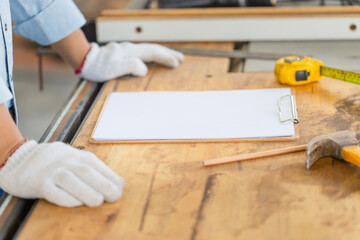 Blank clipboard with white sheet and pencil on carpenter table, Furniture designer planning project at workbench, Man in woodworking shop