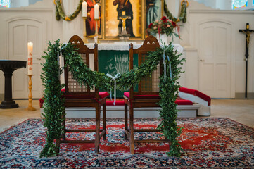 Zwei geschm&uuml;ckte St&uuml;hle stehen vor einem Altar in einer geschm&uuml;ckten Kirche