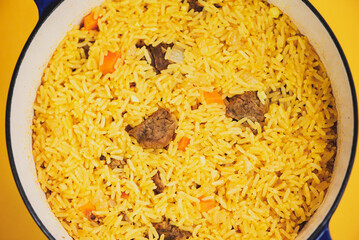 rice with meat in a pan, pilaf on a bright background
