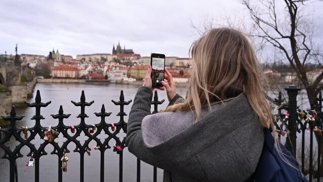 a female traveler takes photos of the panorama of Prague on a smartphone