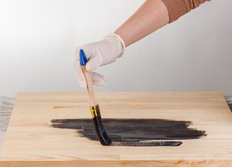 painting wooden background, hand with brush and can of paint