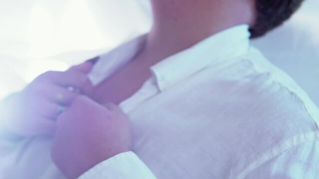 closeup shot of a lgtb man taking off the buttons of his shirt, with long black nails and in slow motion