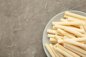 Delicious milk wafer rolls on grey background