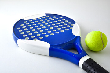 Padel racket and ball on white table elevated view