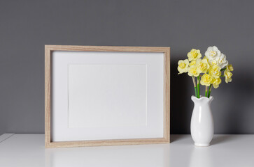 Wooden landscape frame mockup with flowers over grey wall, blank mockup for print presentation