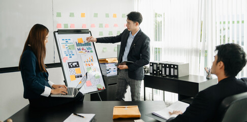 The boss stands near the board with graphs, demonstrates statistics, various personnel attending the training, introduces the new products of the company, in office.