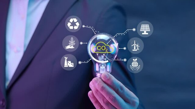 Businessman holding light bulb with icons in co2 environmental concept. Clean energy, renewable energy, Net Zero, Love the world, sustainable energy and reducing global warming.