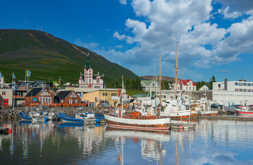 Scenic view of historic town of Husavik in July evening light, blue sky and clouds, north coast of Iceland
