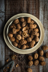 Plate full of walnuts with nutcracker on wooden background