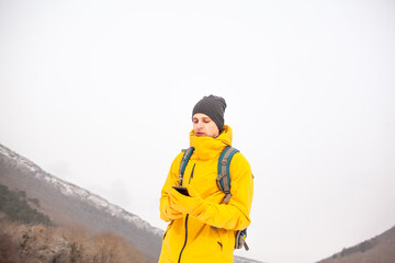 Fototapeta na wymiar The man dresssed yellow warm jacket and trousers, bagpack traveling in the snow landscape