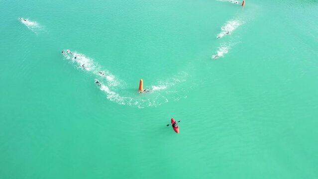 Aerial hover above beautiful turquoise water as triathlon swimmers round buoys - Oamaru Harbor (New Zealand)