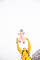 Happy father play and have fun woth baby. Man holding the female toddler in the hands and laughing on a cold winter day