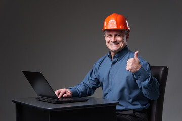 Engineer at his desk with a laptop, showing thumbs up