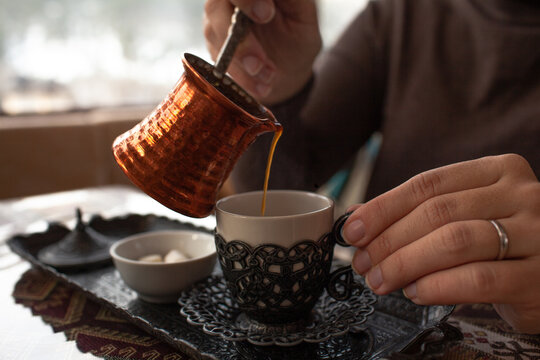 Close-up of hands hold the cup of turkish coffee