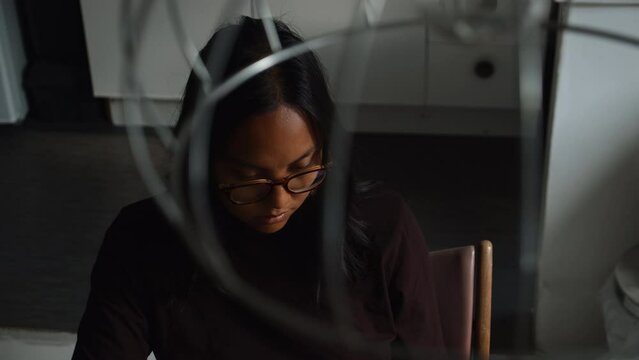 A high angle of an asian woman sitting at her laptop computer in her apartment using a laptop computer to work from home