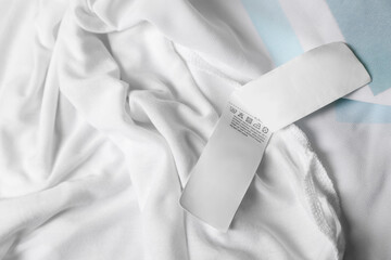 Clothing label on beautiful white garment, top view