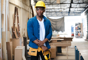 Male carpenter standing in carpentry workshop. A multiracial repairman at work in wood furniture...