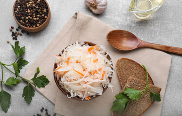Bowl of tasty sauerkraut and ingredients on grey table, flat lay