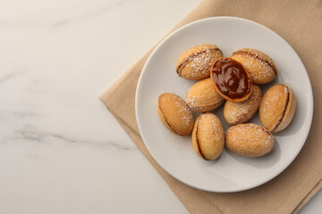 Homemade walnut shaped cookies with boiled condensed milk on white marble table, top view. Space for text
