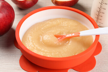 Healthy baby food. Bowl with delicious apple puree on white wooden table, closeup