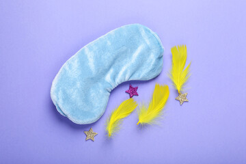 Soft sleep mask, confetti in shape of stars and feathers on purple background, flat lay