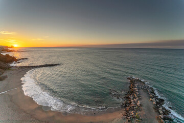 Spectacular sunrise, beach with fine sand and brown, blue sky and the rays of the sun rising on the horizon.