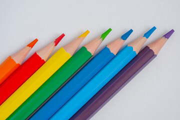 Many different colored pencils on white surface, background - close up, top view. Abstract, creative and education concept