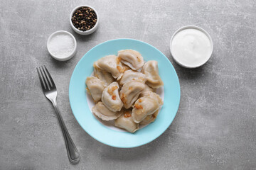 Delicious dumplings (varenyky) with potatoes and onion served on grey table, flat lay