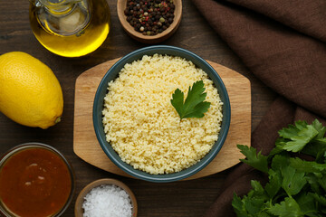Tasty couscous and ingredients on wooden table, flat lay