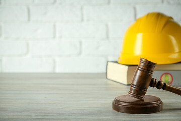Construction and land law concepts. Judge gavel, protective helmet, ruler with book on wooden table, space for text