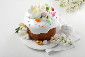 Traditional Easter cake with sprinkles, jelly beans, marshmallows and decorated eggs on white table