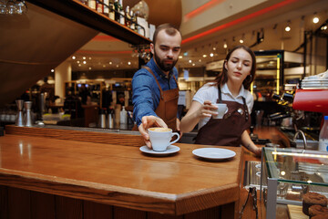 Two baristas work on creating coffee in a coffee shop