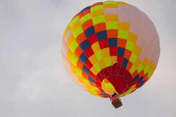 Colorful hot air balloon flying against grey sky at Winter aerostat festival. Freedom, sport, aircraft concept