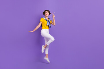 Fototapeta na wymiar Photo of cheerful positive lady wear trendy striped clothes hand demonstrate v-sign empty space isolated on purple color background